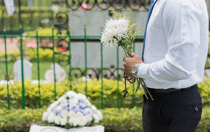 묘 앞에서 꽃 들고 있는 사람